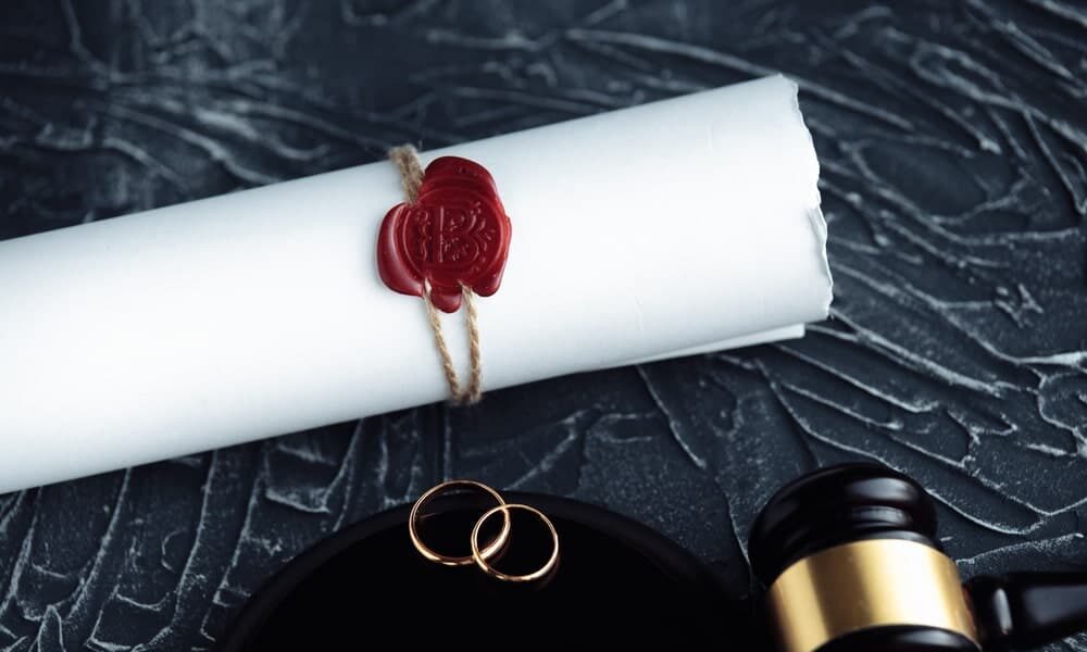 Prenuptial agreements Attorneys Los Angeles County California portrayed by marriage agreement next to wedding bands and gavel on a gray table.